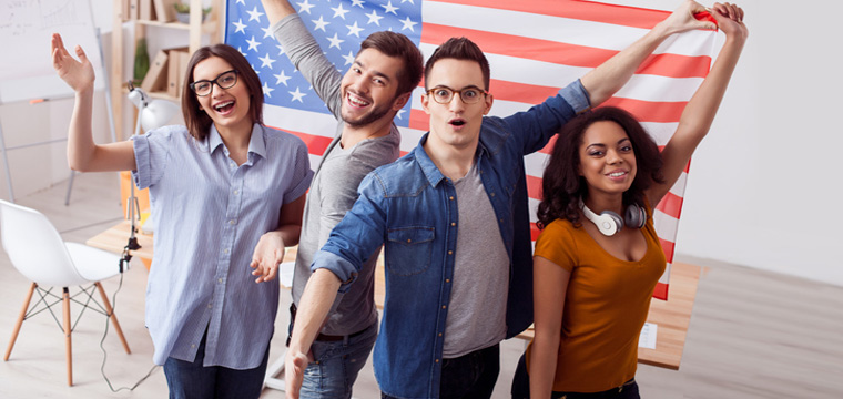 Eine Gruppe junger Studenten jubelt vor einer US-Flagge.